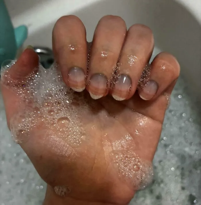 Human anatomy photo of hand covered in soap suds showing visible nail bed details