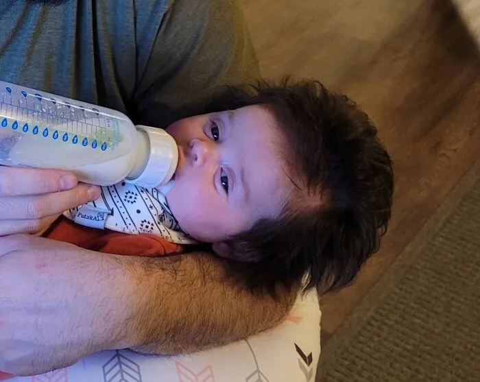A newborn baby with a full head of thick dark hair, showing unique human anatomy features.