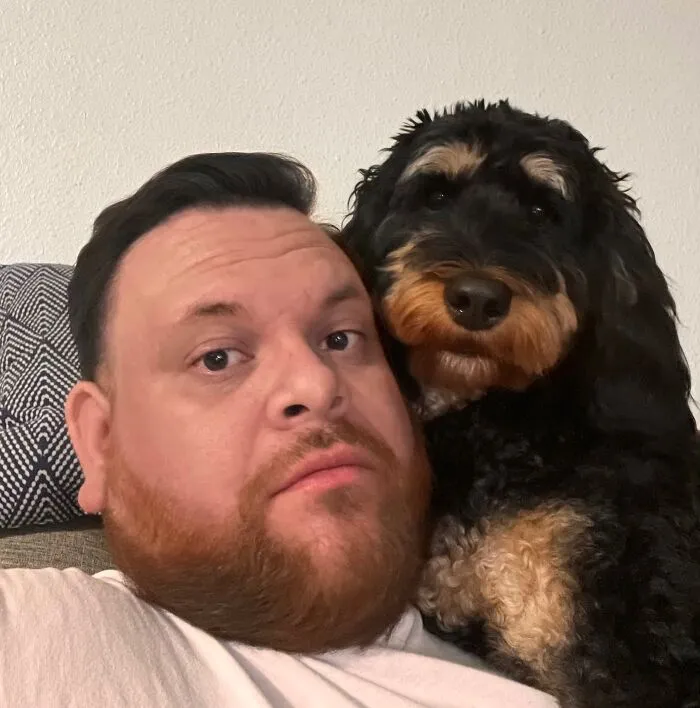 A man with a red beard next to his dog that looked like its owner with a similar black and tan pattern