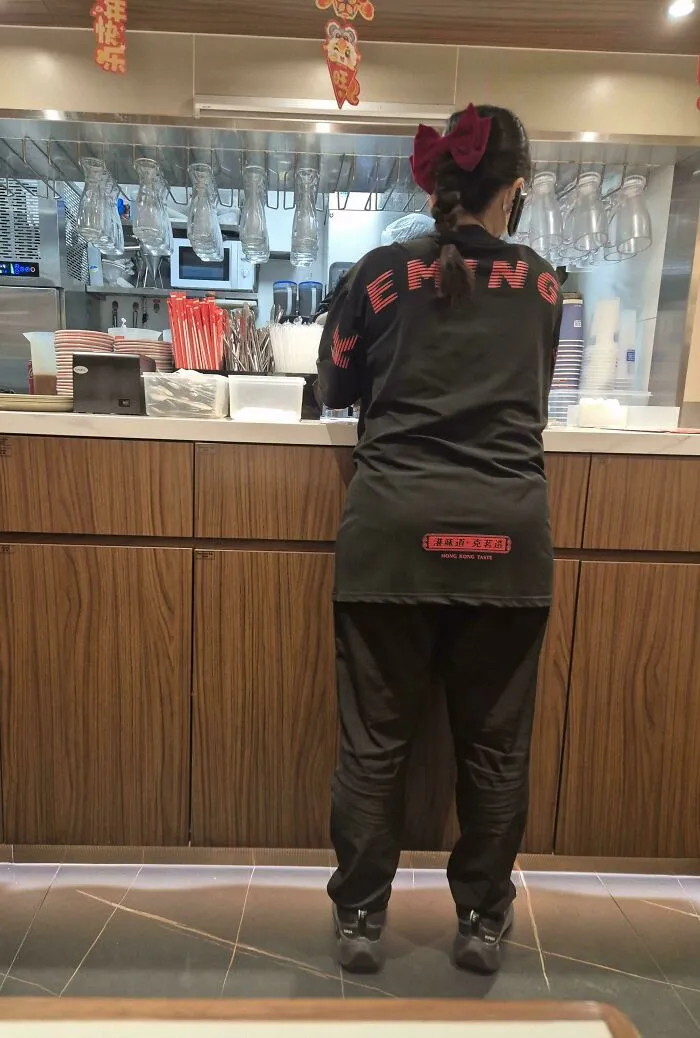 Close-up on a staff member wearing a shirt with bad letter spacing, an example of funny typography fails.