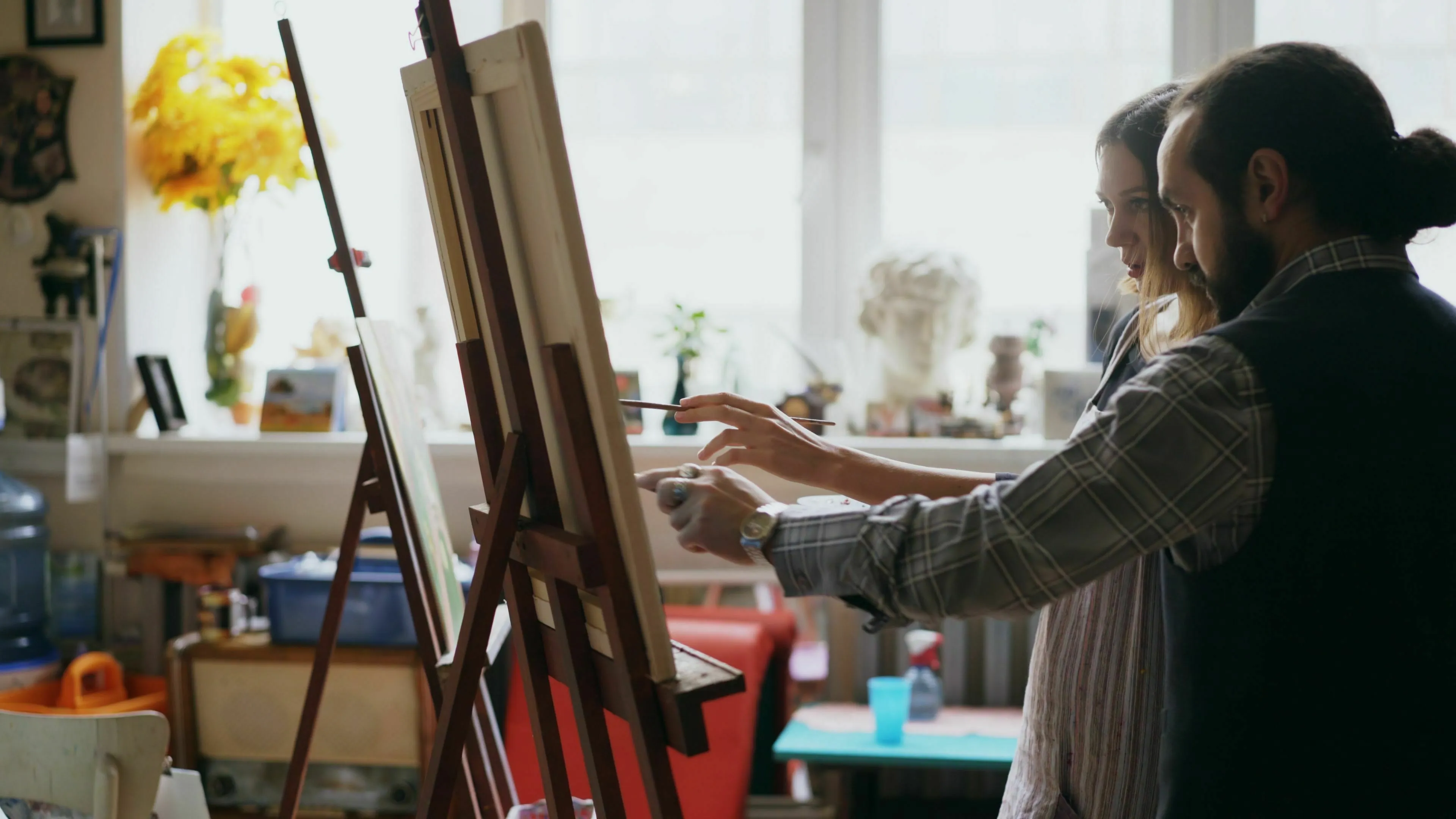 An artist teaching a student how to paint on a canvas, inspired by a famous painting.