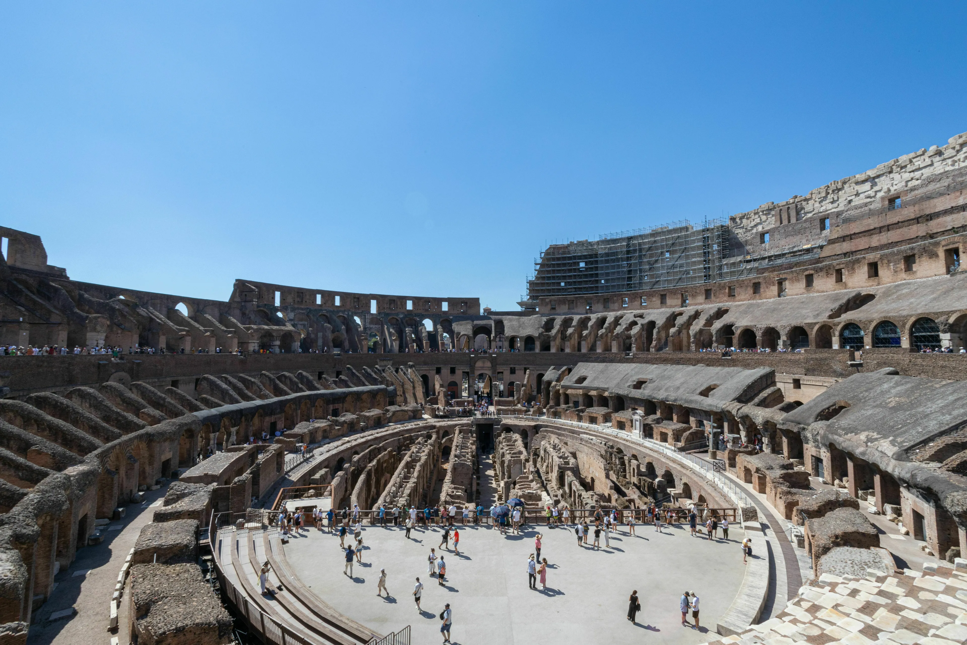 A wide-angle view of the interior ruins and seating areas of the Colosseum in Rome.
