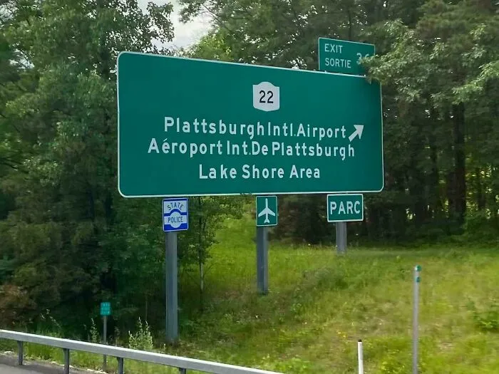 A green highway sign featuring a typography fail with poor letter spacing in Plattsburgh Intl Airport.