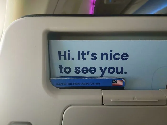 An airplane seat pocket card with a subtle typography fail in the letter spacing of the word Hi.