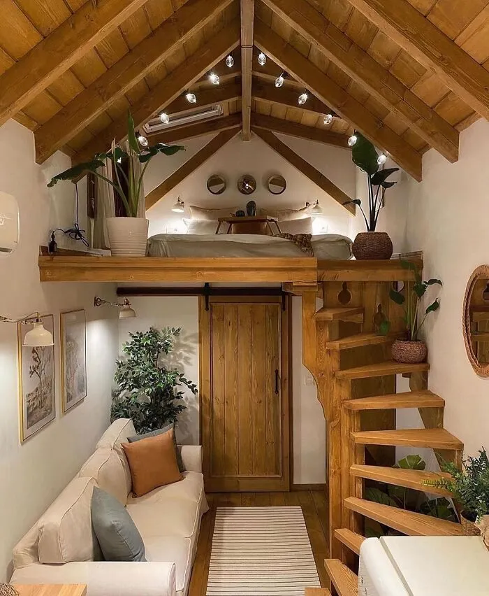 Tiny home interior showcasing clever wooden creations with a loft bed and spiral stairs.