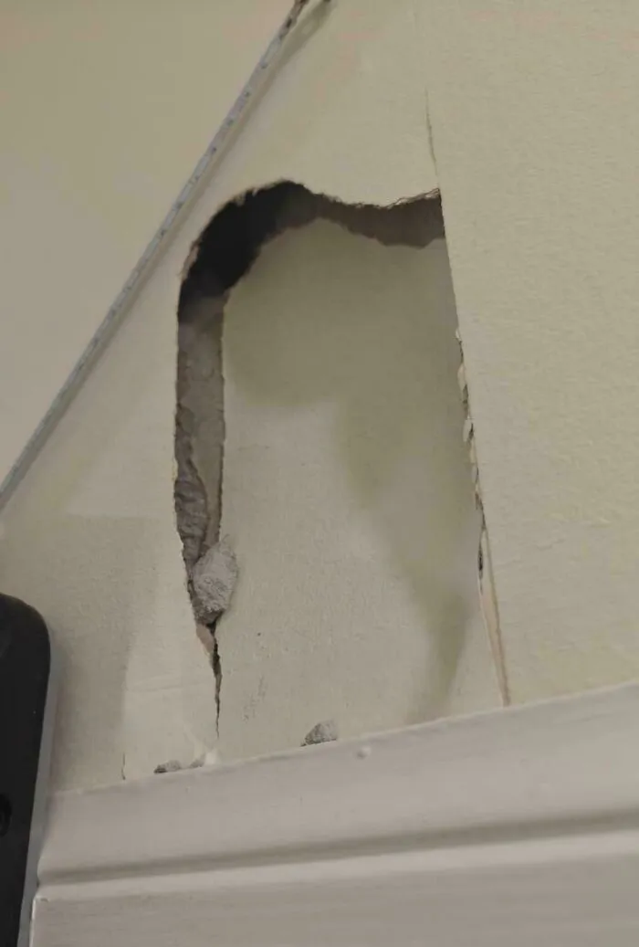 A questionable decision depicting a damaged wall with plaster broken and peeling near a white trim