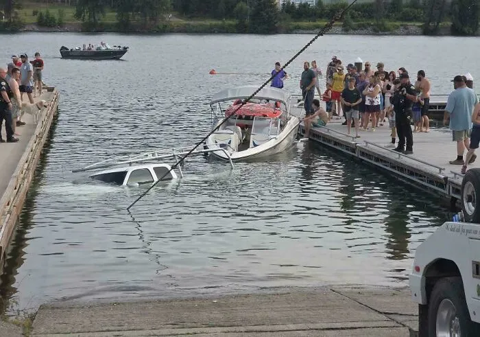 A white truck submerged in water next to a boat dock showcasing a questionable decision at the boat launch