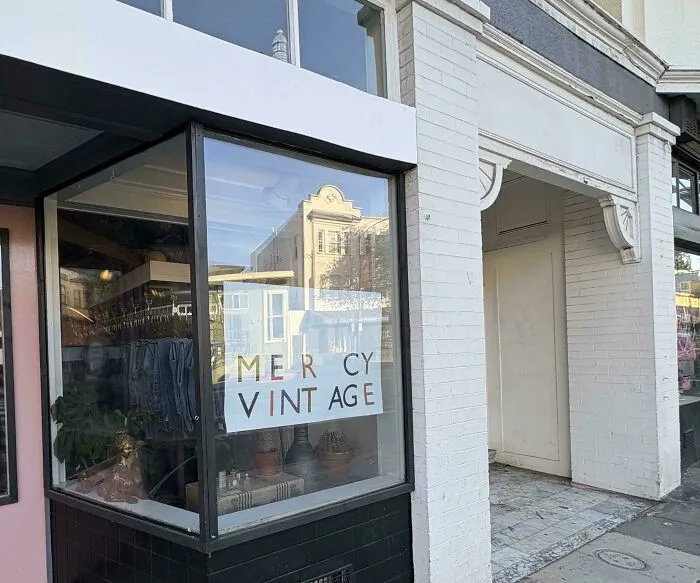Shop window sign showing a typography fail with wide letter spacing reading Mercy Vintage