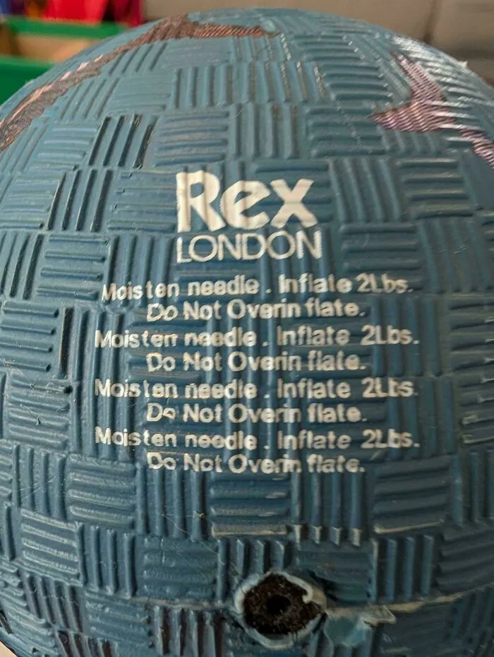 Close-up of a blue toy ball showing repeated text with confusing spacing, showcasing typography fails.
