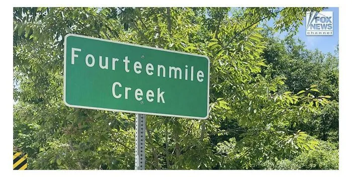 Green road sign with terrible letter spacing spelling Fourteenmile Creek, showcasing bad typography fails.