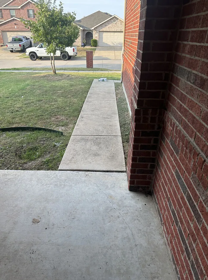 A narrow sidewalk built right next to a brick wall showing questionable construction decisions