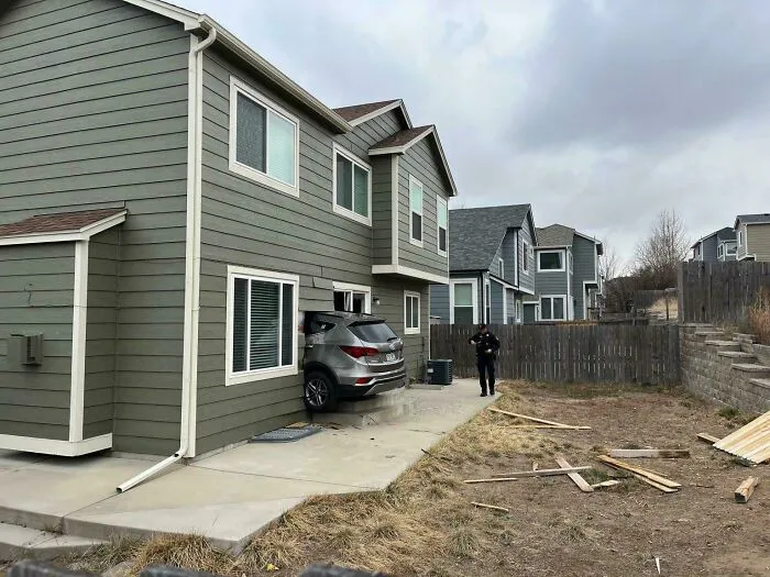 A silver SUV crashed into the side of a house, showcasing a highly questionable driving decision