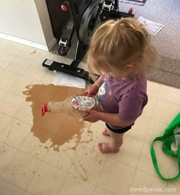 A toddler pouring syrup on the kitchen floor, highlighting questionable decisions in parenting.