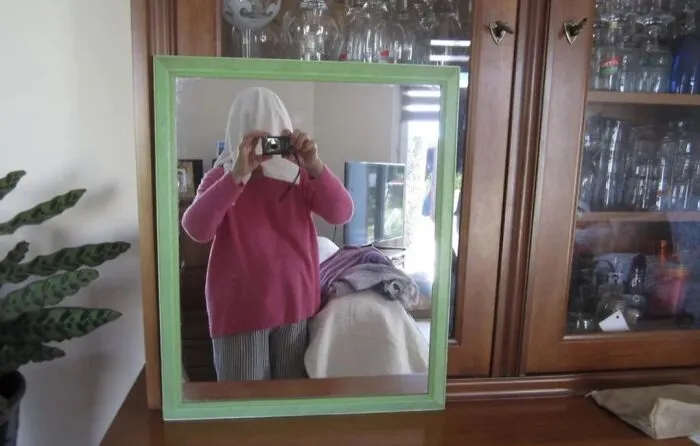 Funny mirror pics of a person covering their head with a cloth while taking a selfie reflection.