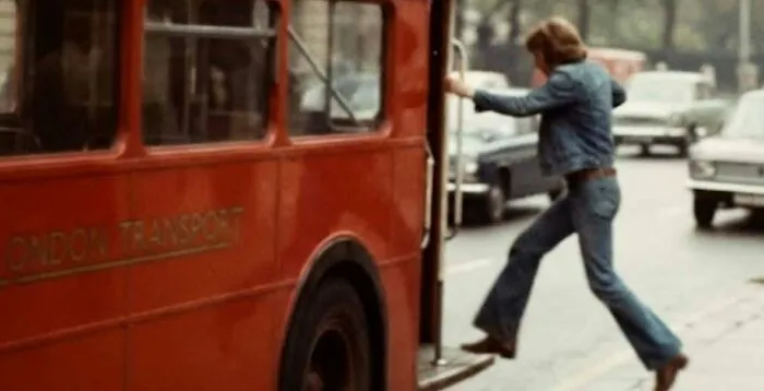 Person boarding a red 1970s London Transport double-decker bus