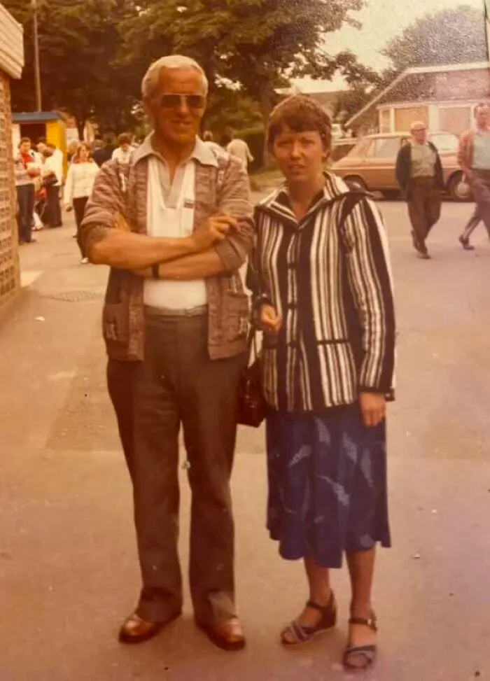 Couple in vintage 70s clothing posing on a sidewalk in old photo