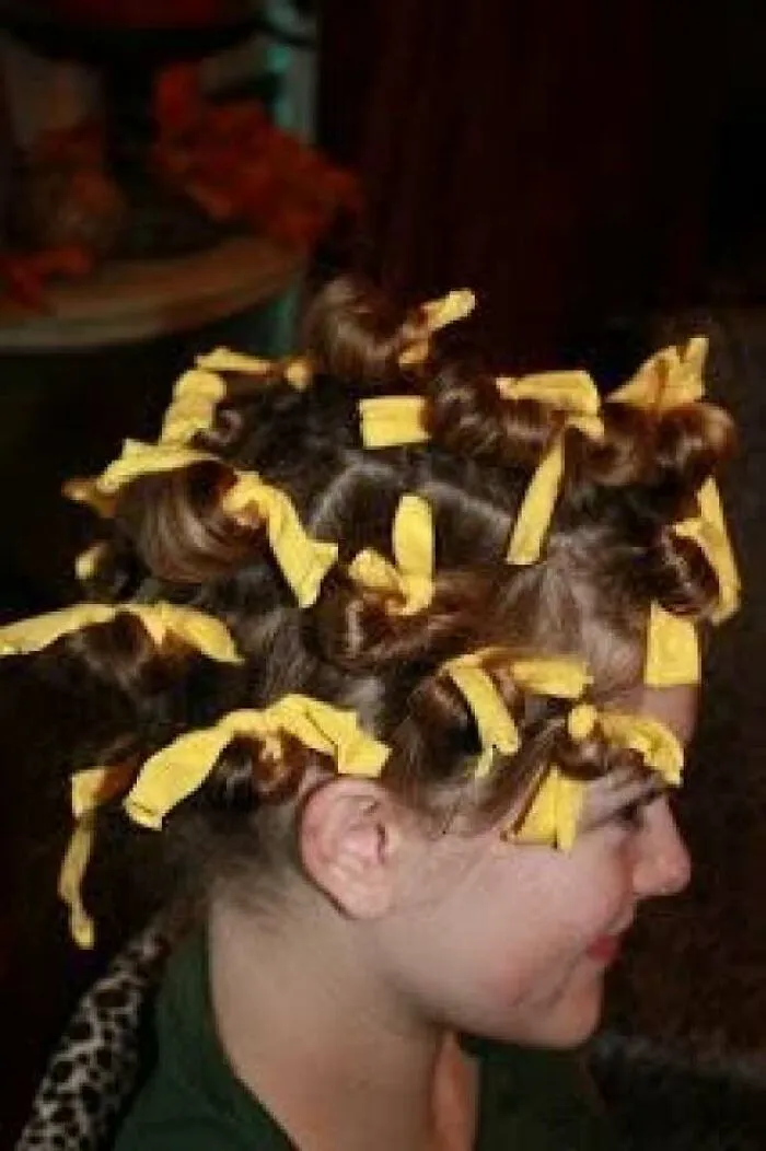 1970s hairstyle with rolled curls tied with yellow ribbons on a woman's head