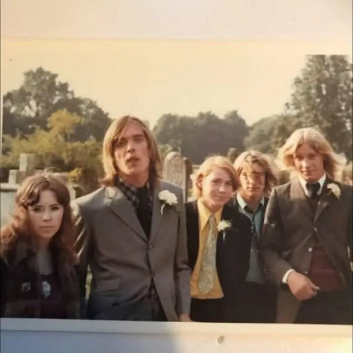 Group of young people dressed in 1970s style suits and dresses posing outdoors