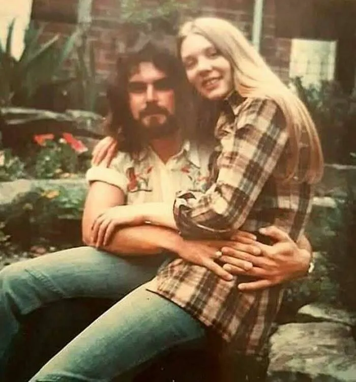 Vintage 70s couple embracing outdoors in casual plaid and denim