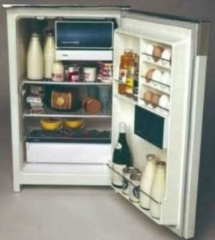 Vintage 1970s refrigerator stocked with bottles and jars inside an old kitchen appliance
