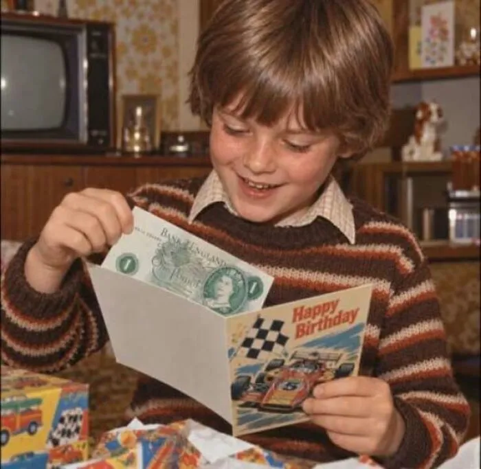 Boy opening a 1970s birthday card with cash inside in a cozy retro living room