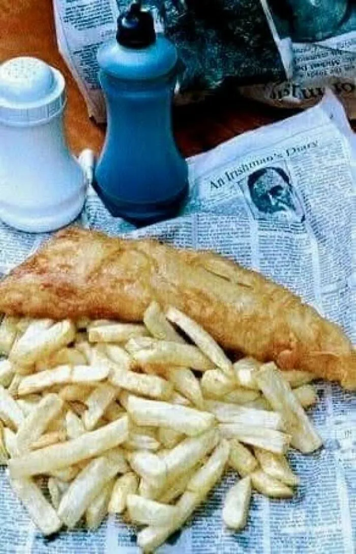 Classic 70s fish and chips meal on newspaper with condiments