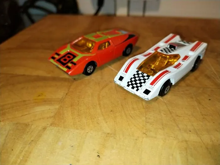 Two vintage 70s toy race cars on wooden surface closeup