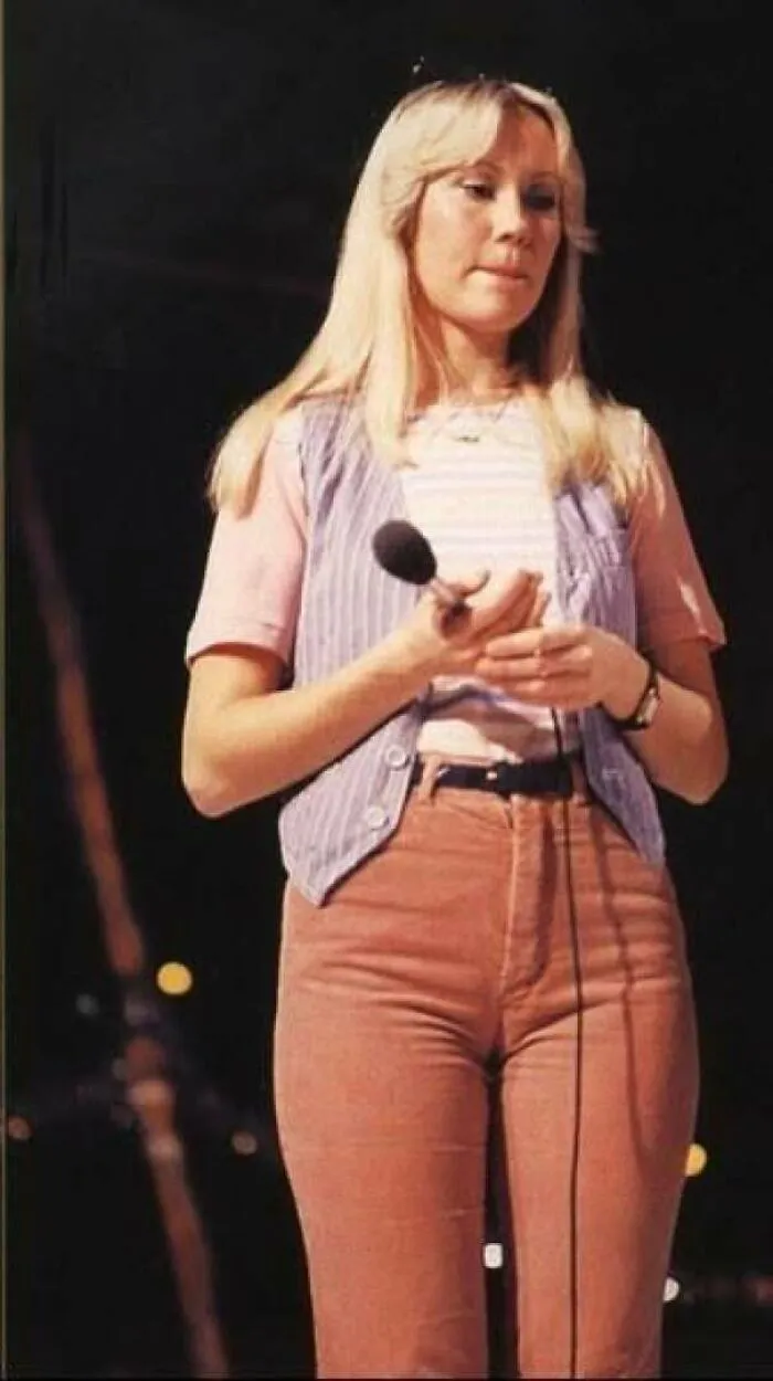 1970s photo of woman in vintage clothes holding microphone on stage