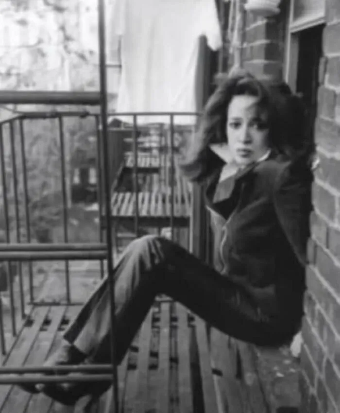 1970s vintage photo of woman sitting on metal fire escape outside brick building