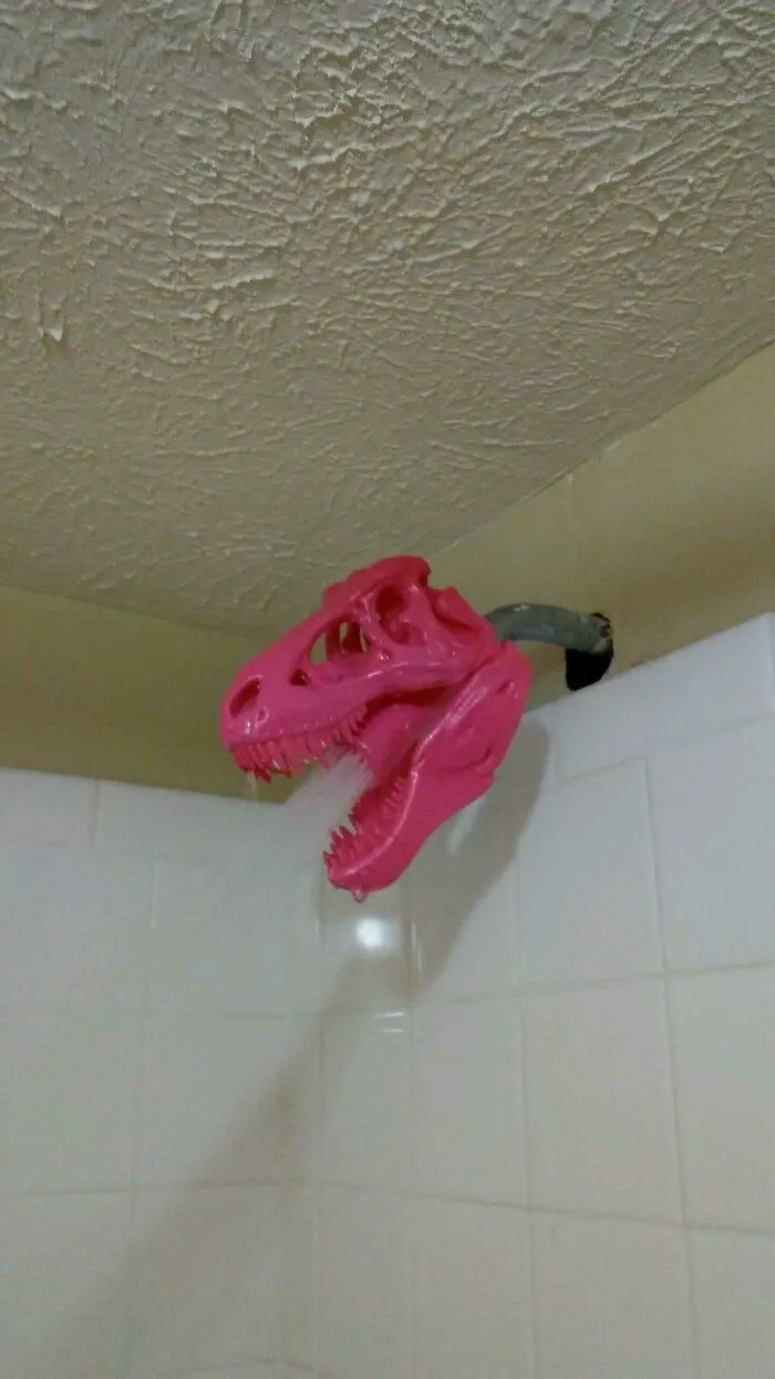 A pink T-Rex skull shower head attachment made using a 3D printer