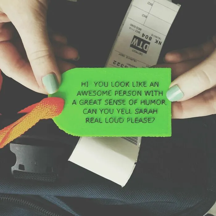 Hands holding a green luggage tag with a humorous message made using a 3D printer.