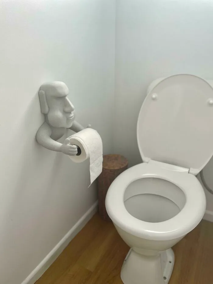A fun Moai statue toilet paper holder on a bathroom wall made by a 3D printer