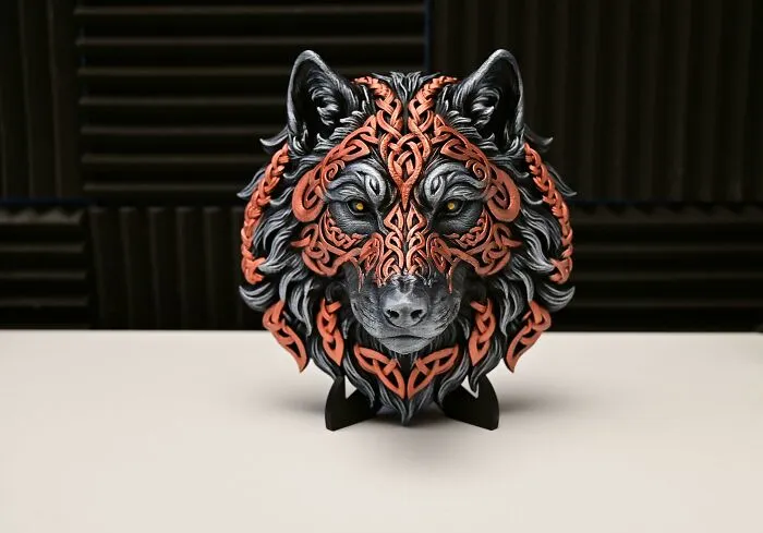 A detailed 3D printed wolf head sculpture with intricate orange Celtic patterns.