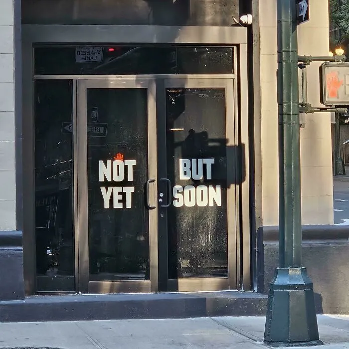 Storefront glass doors with confusing text alignment, showing badly designed signs.