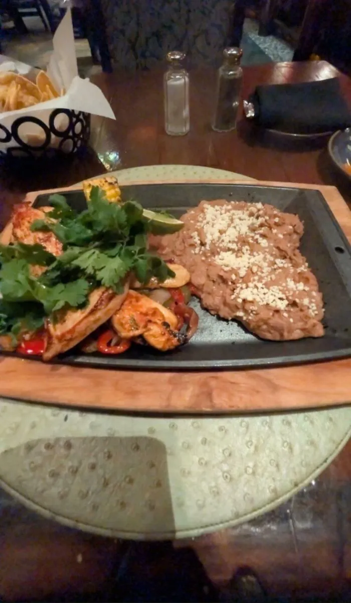 Questionable food combos showing a sizzling platter with grilled meat, cilantro, and refried beans.