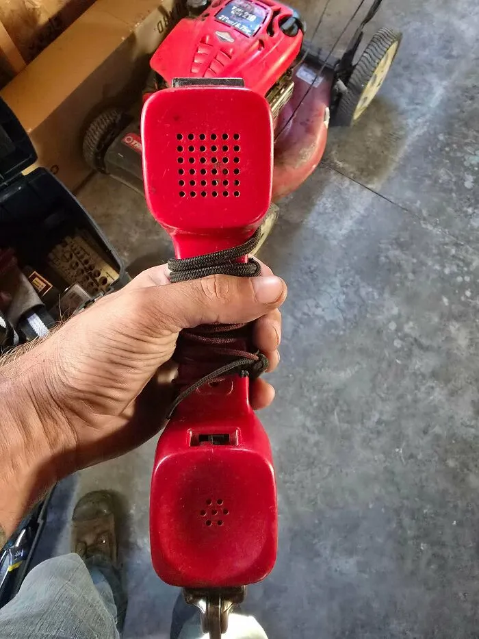 Hand holding a vintage red telephone handset as an example of classic retro gadgets in a workshop