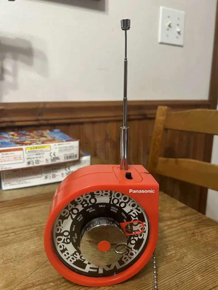 Orange Panasonic retro gadgets radio with a circular frequency dial and silver antenna sitting on a wooden table