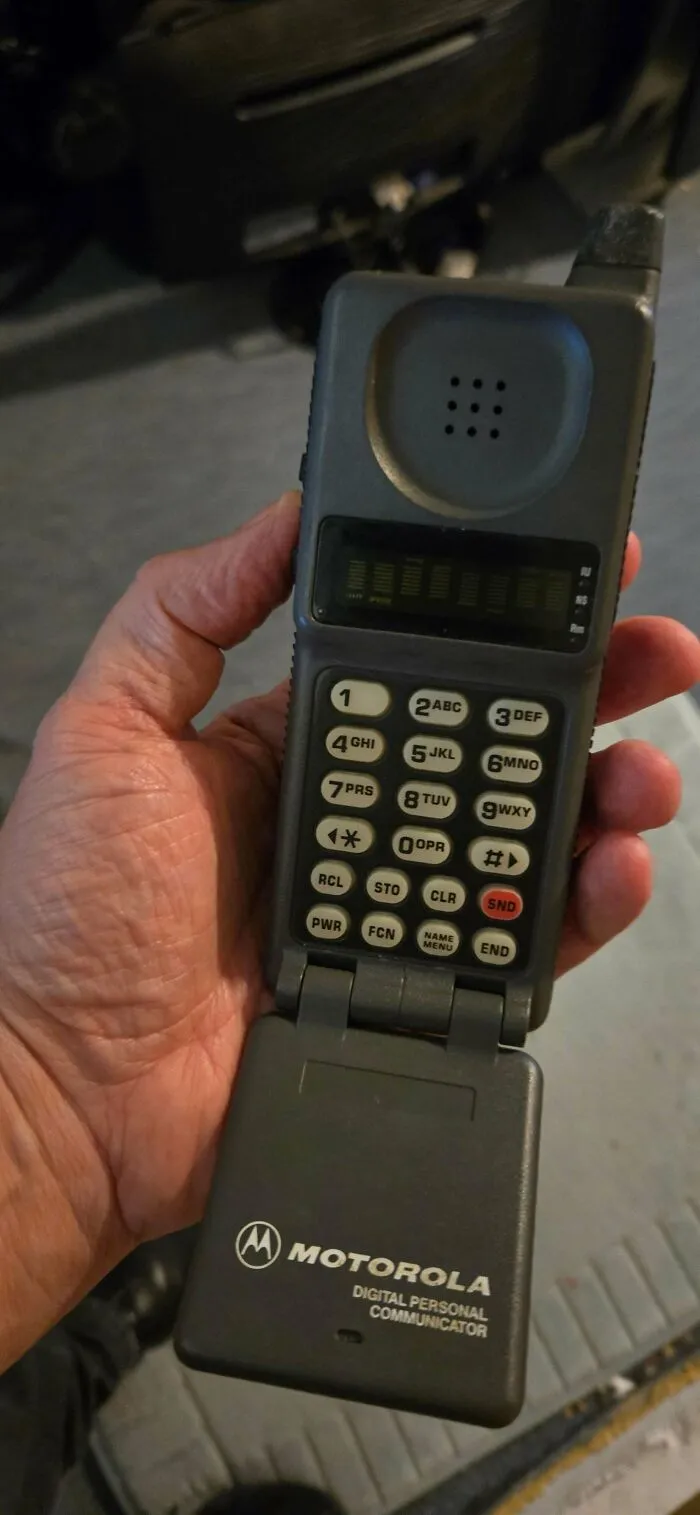 A person holding a vintage Motorola flip phone illustrating early mobile retro gadgets