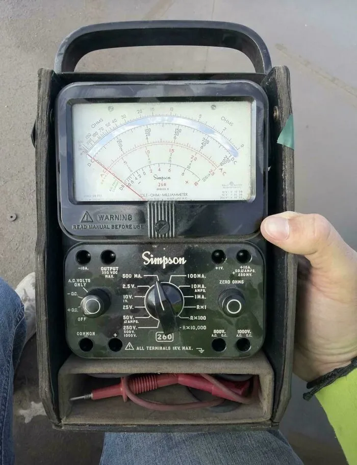 A person holding an analog Simpson 260 multimeter, a classic example of retro gadgets and vintage tech.