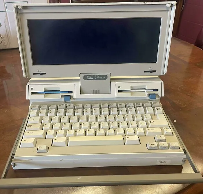 A vintage beige IBM PC Convertible laptop open on a table, displaying classic retro gadgets technology.