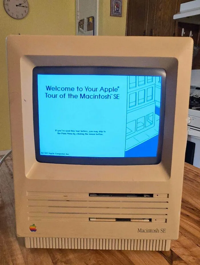 A vintage Apple Macintosh SE computer displaying a welcome screen, showcasing retro gadgets and vintage technology.