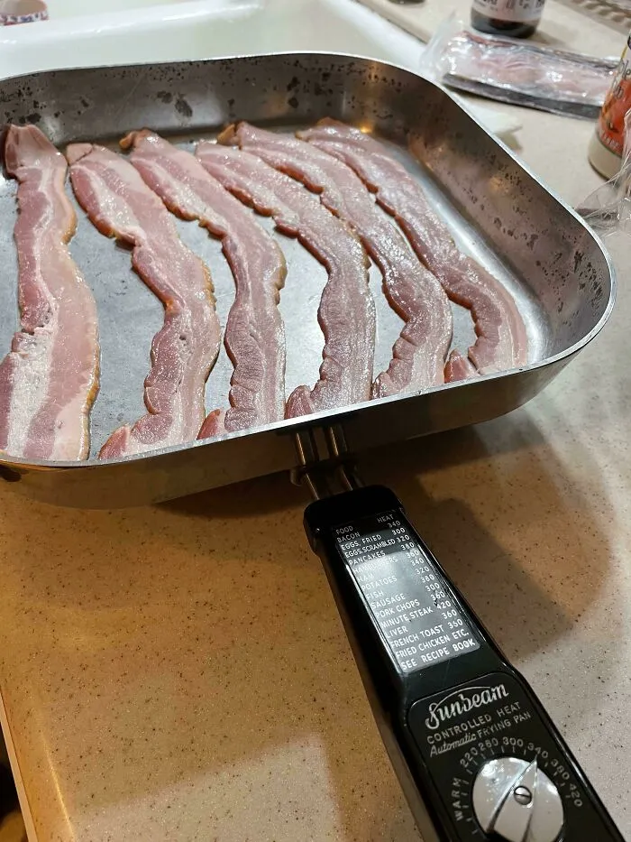 Slices of bacon cooking in a vintage Sunbeam electric pan, highlighting practical retro gadgets.