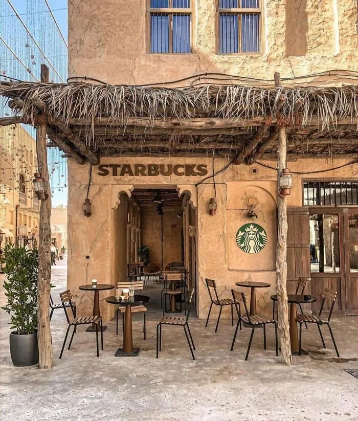 A Starbucks cafe built with traditional rustic stone and thatched roof architecture, captured in strange photos.
