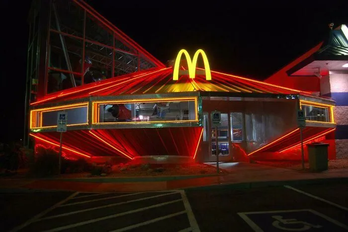 A strange photo of a spaceship-shaped McDonald's restaurant glowing with neon lights at night.