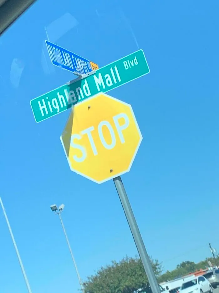 A strange photo of a bright yellow stop sign with white letters on a street post under a clear blue sky.