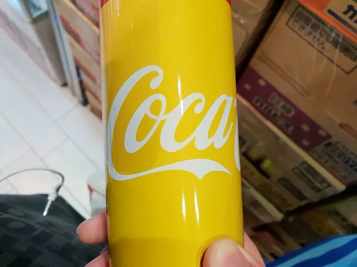 A hand holding a yellow Coca-Cola can featured in strange photos.