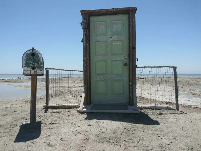 A standalone green door and mailbox on a sandy beach, among strange photos that challenge reality.