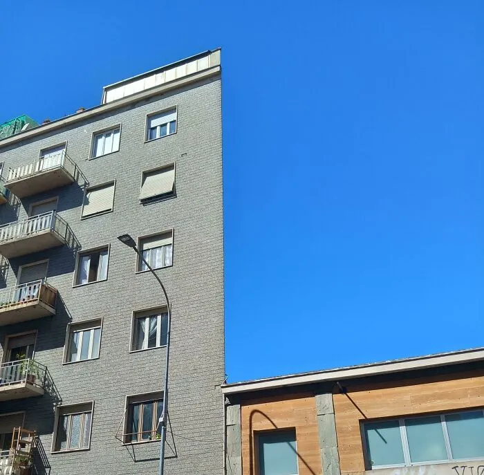 An optical illusion of a flat building facade against a blue sky, creating a strange photo of missing reality.