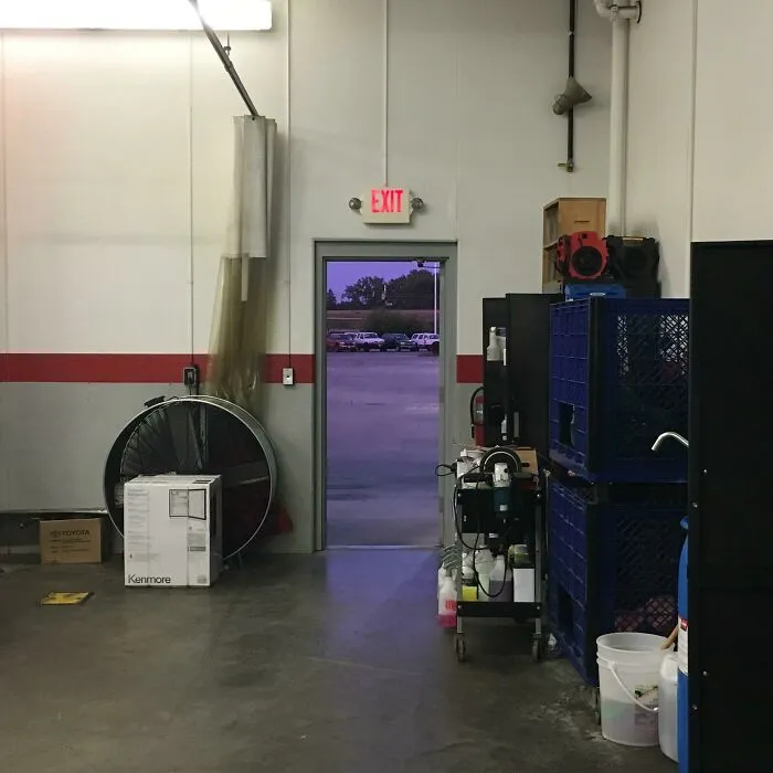 An open exit doorway leading to a purple sky in a garage, featured in strange photos of surreal views.
