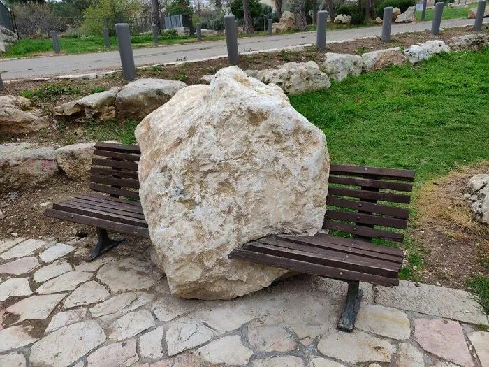 Strange photos showing a large rock placed directly in the middle of a wooden park bench